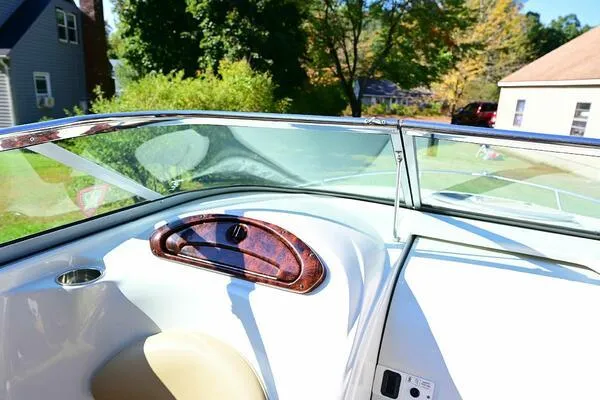 Slide: The Image of 2015 Crownline 236 SC boat interior with windshield and dashboard, set in a sunny residential area. - 44