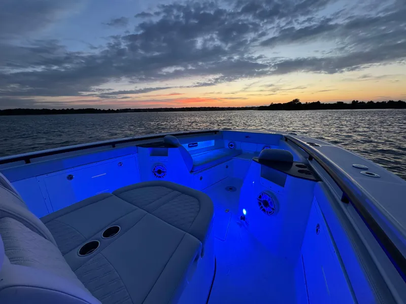 Slide: The Image of 2025 Crevalle 33 CSF boat with blue interior lighting at sunset on the water. - 14