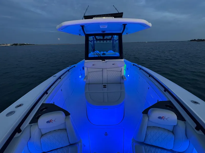 Slide: The Image of 2025 Crevalle 33 CSF boat with blue LED lights on open water at dusk. - 16