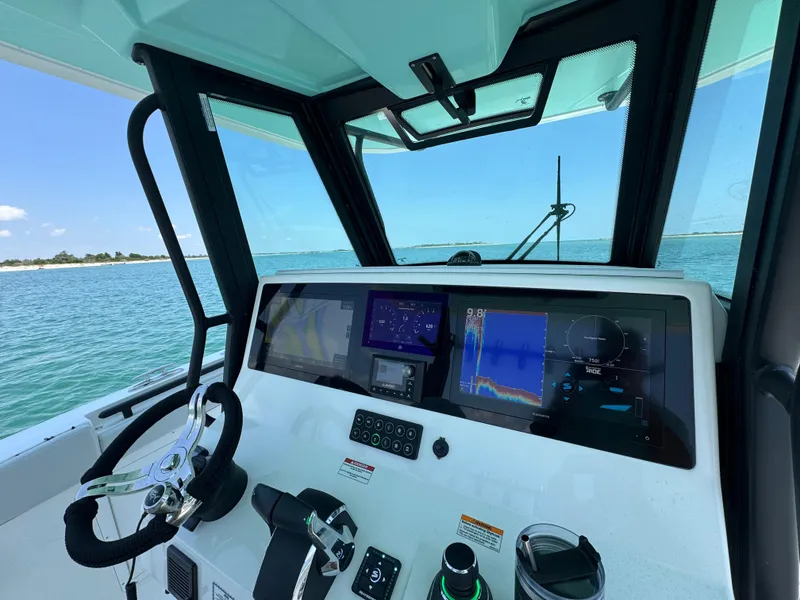 Slide: The Image of 2025 Crevalle 33 CSF boat dashboard with navigation screens, steering wheel, and ocean view. - 23
