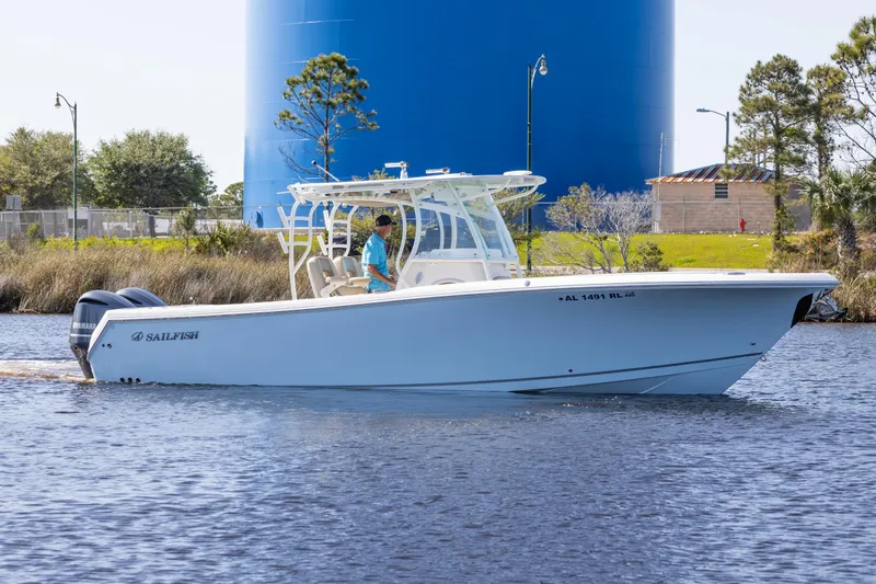 Slide: The Image of 2018 Sailfish 290 CC boat cruising on a calm waterway near a blue water tower. - 0
