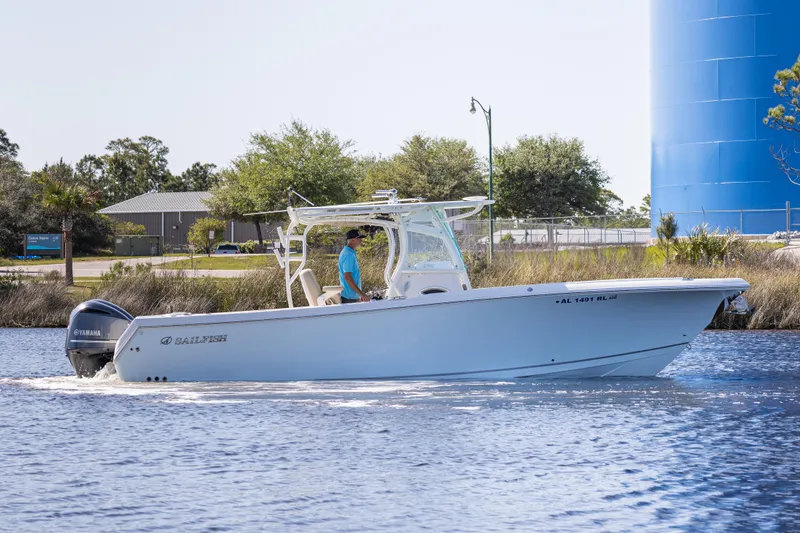 Slide: The Image of 2018 Sailfish 290 CC boat cruising on a calm waterway near a blue water tower. - 1