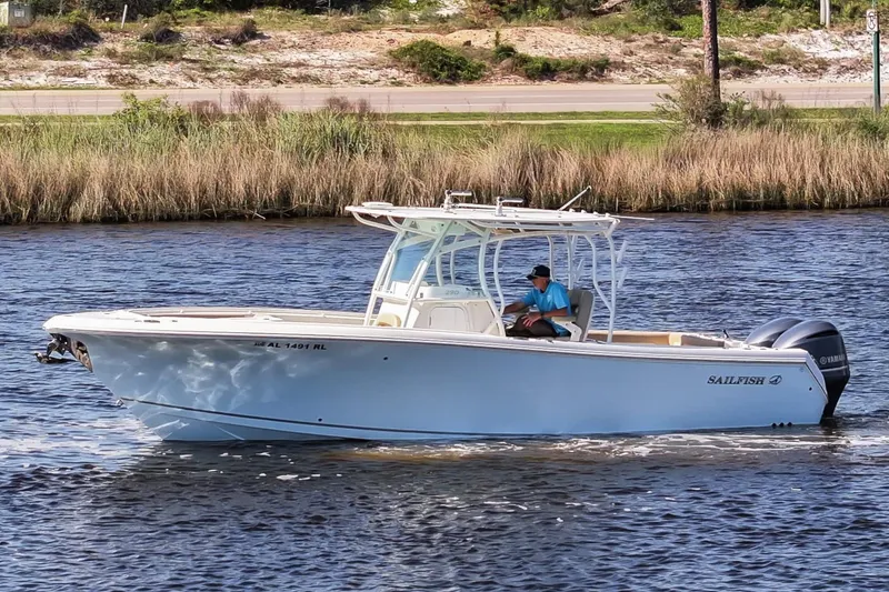 Slide: The Image of 2018 Sailfish 290 CC boat cruising on a calm river with a person at the helm. - 11