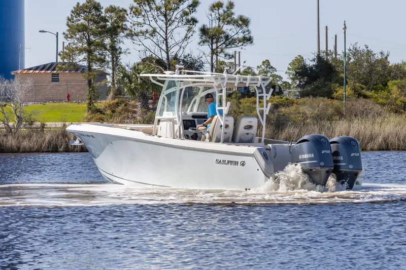 Slide: The Image of 2018 Sailfish 290 CC boat cruising on a calm river with twin outboard engines. - 2