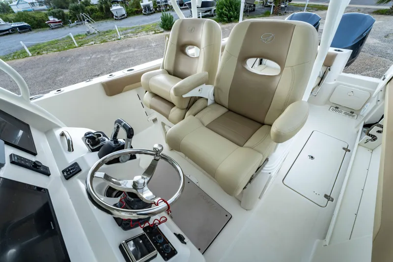 Slide: The Image of 2018 Sailfish 290 CC boat cockpit with dual beige captain chairs and steering wheel. - 21