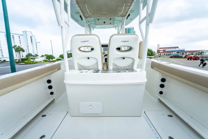 Slide: The Image of 2018 Sailfish 290 CC boat interior with dual seats and storage, docked in a marina. - 24