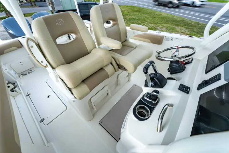 Slide: The Image of 2018 Sailfish 290 CC boat cockpit with dual beige seats and modern controls. - 28