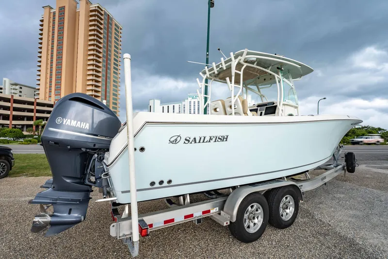 Slide: The Image of 2018 Sailfish 290 CC boat on trailer, featuring Yamaha outboard motor, parked near tall buildings. - 36