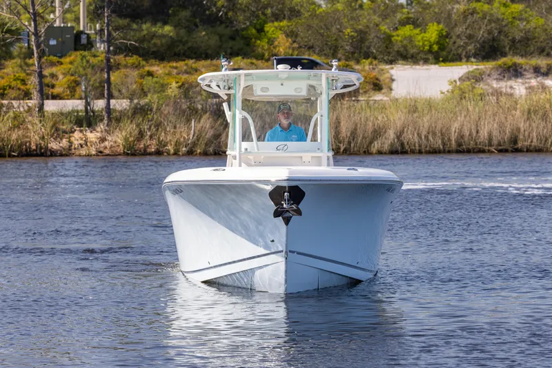 Slide: The Image of 2018 Sailfish 290 CC boat cruising on a calm waterway, surrounded by lush greenery. - 5