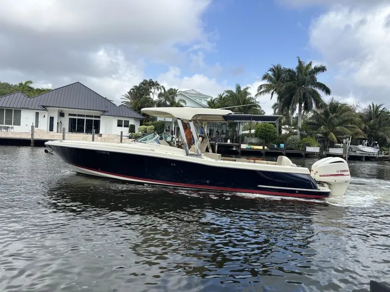 Slide: The Image of 2019 Chris-Craft Calypso 30 boat cruising on a calm waterway, surrounded by palm trees. - 13