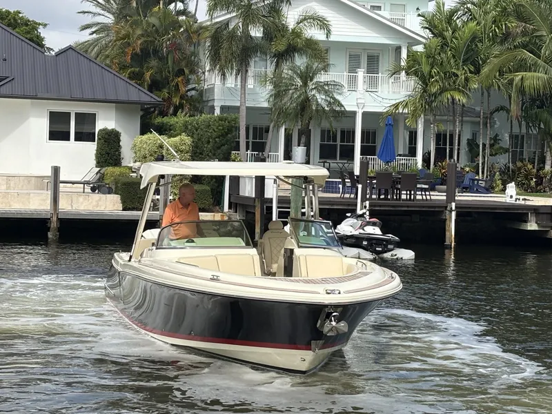 Slide: The Image of 2019 Chris-Craft Calypso 30 boat cruising near waterfront homes with palm trees. - 2