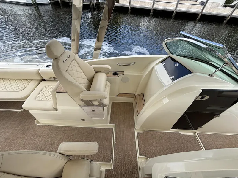 Slide: The Image of 2019 Chris-Craft Calypso 30 boat interior with luxurious seating and helm, docked by the water. - 7