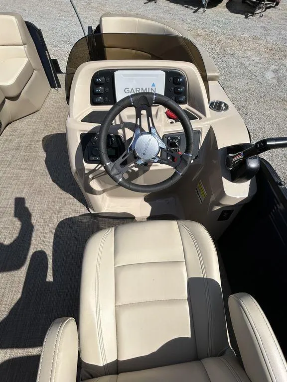 Slide: The Image of 2022 Manitou 21 Aurora LE RF VP II boat dashboard with Garmin display and beige seating. - 4