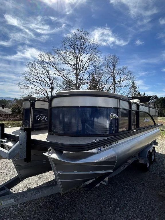 Slide: The Image of 2022 Manitou 21 Aurora LE RF VP II pontoon boat on trailer under a clear sky. - 6