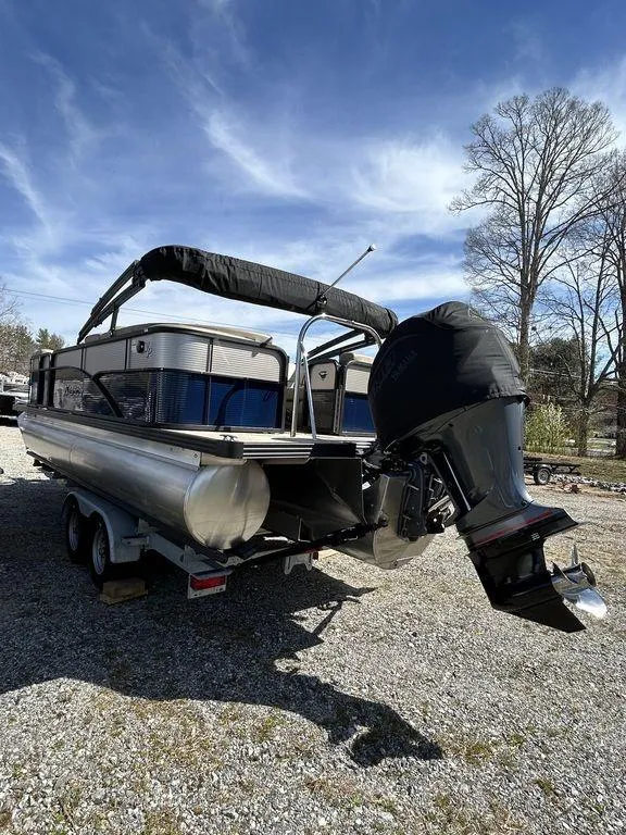 Slide: The Image of 2022 Manitou 21 Aurora LE RF VP II pontoon boat on trailer, outdoors under blue sky. - 7