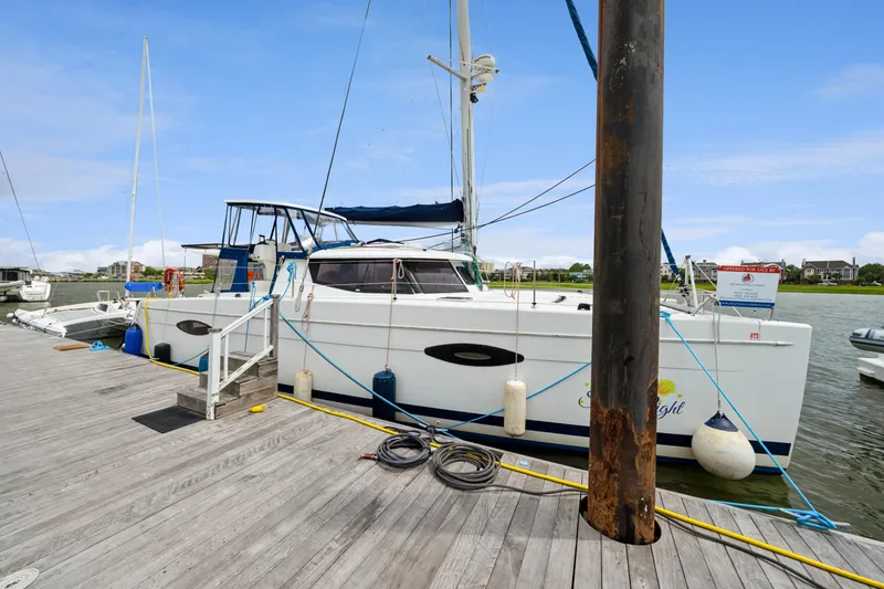Slide: The Image of 2014 Fountaine Pajot Helia 44 catamaran docked at a marina, clear sky background. - 12