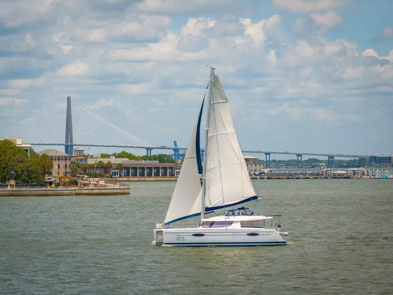 Slide: The Image of Sailing catamaran Fountaine Pajot Helia 44, 2014, on a scenic waterway with bridge backdrop. - 6