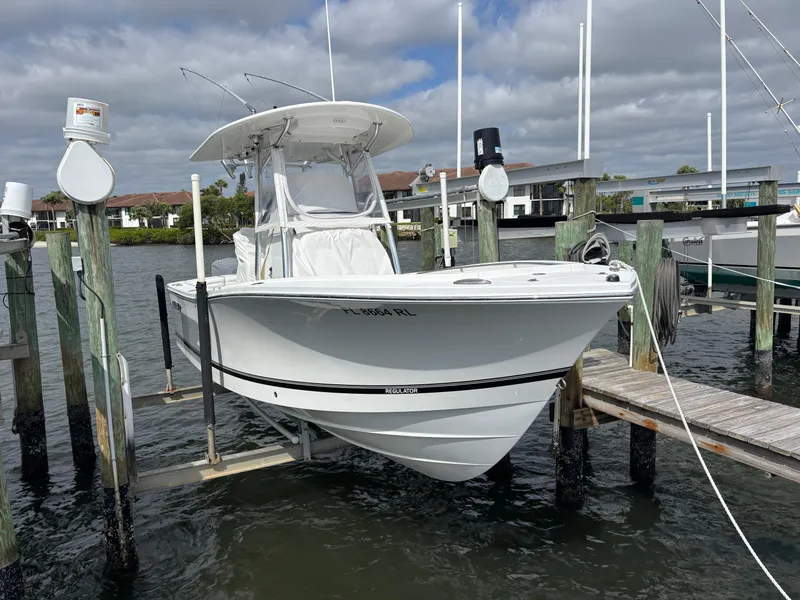 Slide: The Image of 2018 Regulator 23 Forward Seating boat docked at marina under cloudy sky. - 1