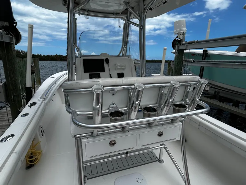 Slide: The Image of 2018 Regulator 23 Forward Seating boat docked, featuring rod holders and a sleek console design. - 15