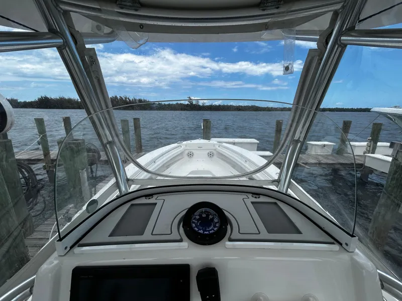 Slide: The Image of 2018 Regulator 23 Forward Seating boat docked, view from helm, clear sky, calm water. - 20