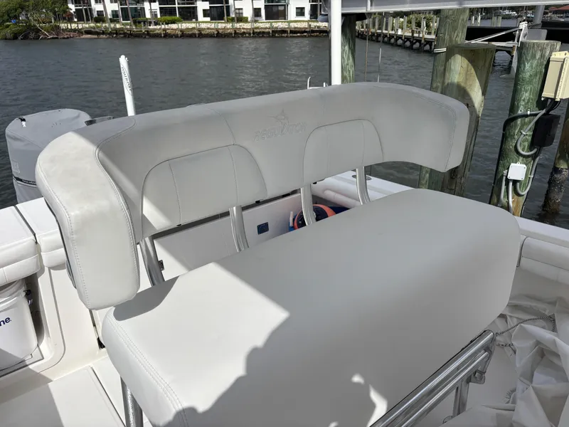 Slide: The Image of 2018 Regulator 23 Forward Seating boat with white cushioned seats, docked by the water. - 29