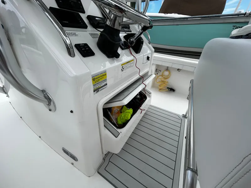 Slide: The Image of 2018 Regulator 23 Forward Seating boat console with storage compartment open. - 30