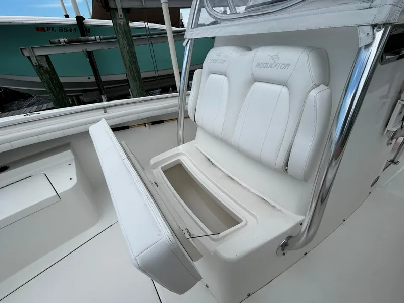 Slide: The Image of 2018 Regulator 23 Forward Seating boat with open storage compartment and white cushioned seats. - 32