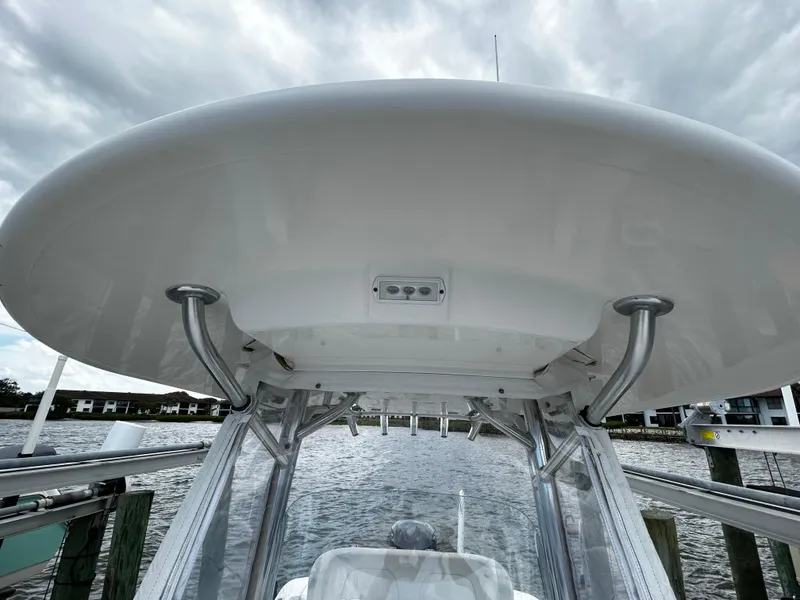 Slide: The Image of 2018 Regulator 23 Forward Seating boat, view of T-top and supports, docked by the water. - 37