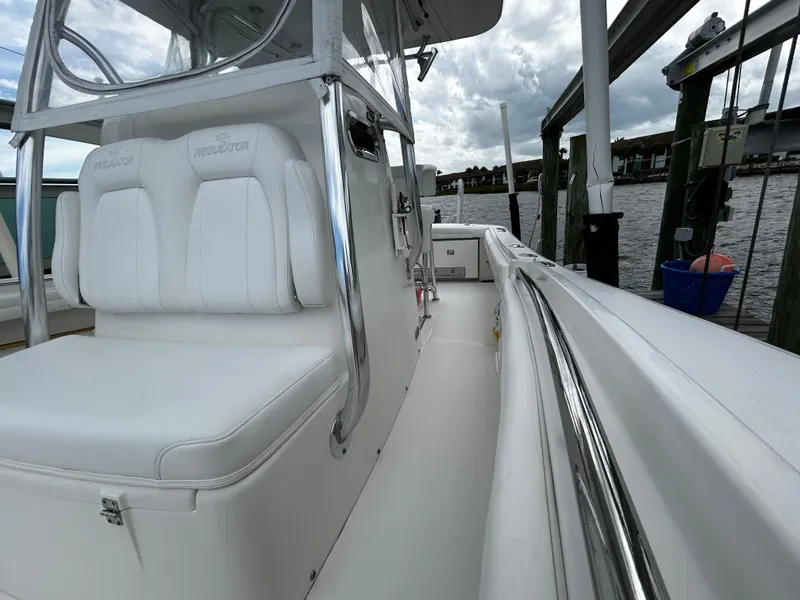 Slide: The Image of 2018 Regulator 23 Forward Seating boat docked, showcasing sleek white seating and polished metal details. - 41