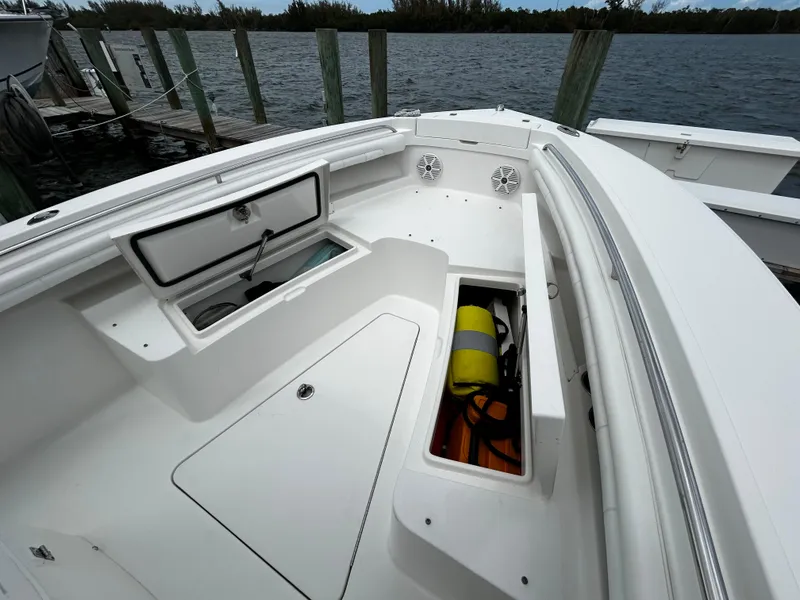 Slide: The Image of 2018 Regulator 23 Forward Seating boat with open storage compartments by the water. - 44