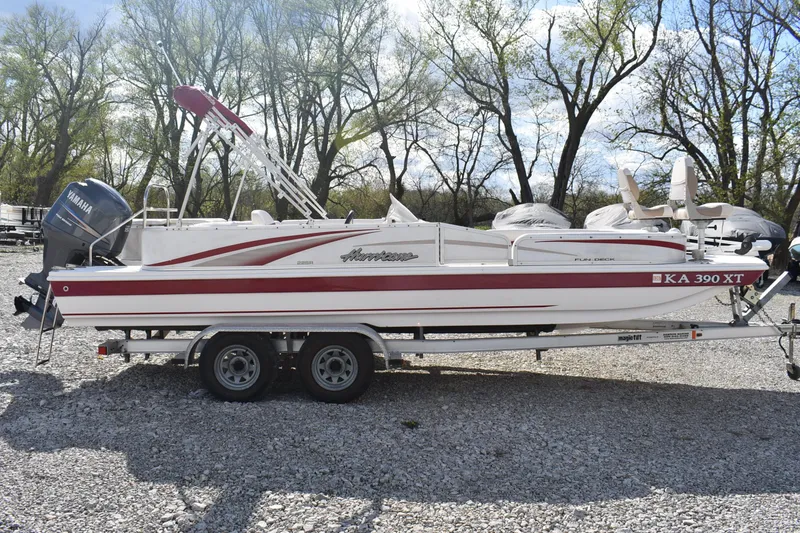 Slide: The Image of 2006 Hurricane FunDeck 228 RE boat on trailer, parked on gravel with trees in background. - 0