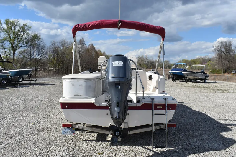 Slide: The Image of 2006 Hurricane FunDeck 228 RE boat with outboard motor, parked on gravel under cloudy sky. - 5