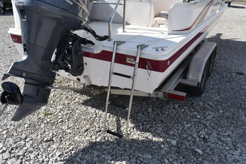 Slide: The Image of 2006 Hurricane FunDeck 228 RE boat with outboard motor and ladder on gravel surface. - 7