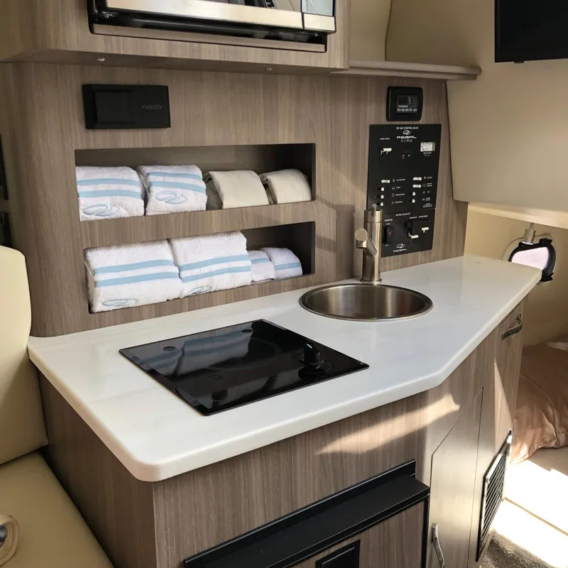 Slide: The Image of Modern kitchenette in 2022 Regal 26 XO boat with sink, stove, and storage shelves. - 25