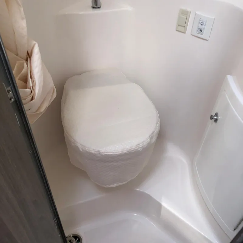 Slide: The Image of 2022 Regal 26 XO boat bathroom with compact toilet and white interior. - 27