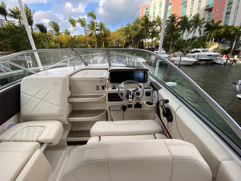 Slide: The Image of 2022 Regal 26 XO boat interior with steering wheel, docked near palm trees and waterfront buildings. - 7