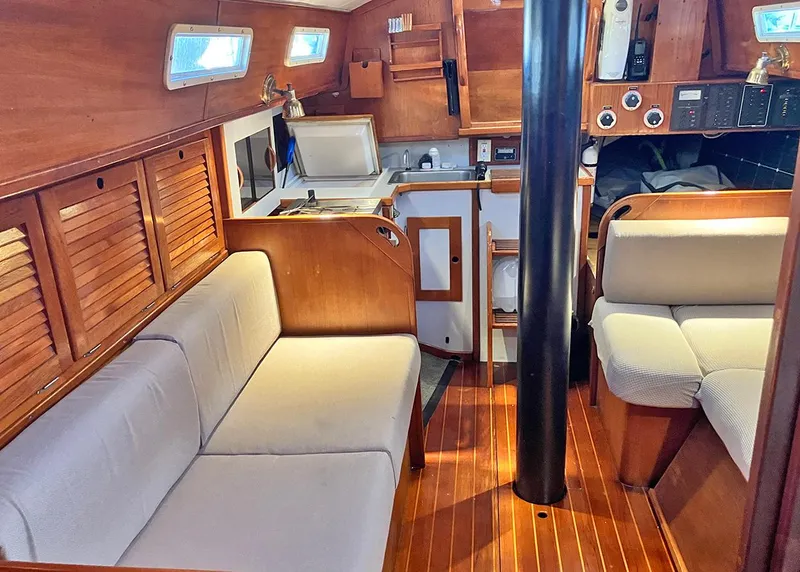 Slide: The Image of 1983 Freedom Cat Ketch interior with wooden finish, cozy seating, and compact kitchen area. - 10