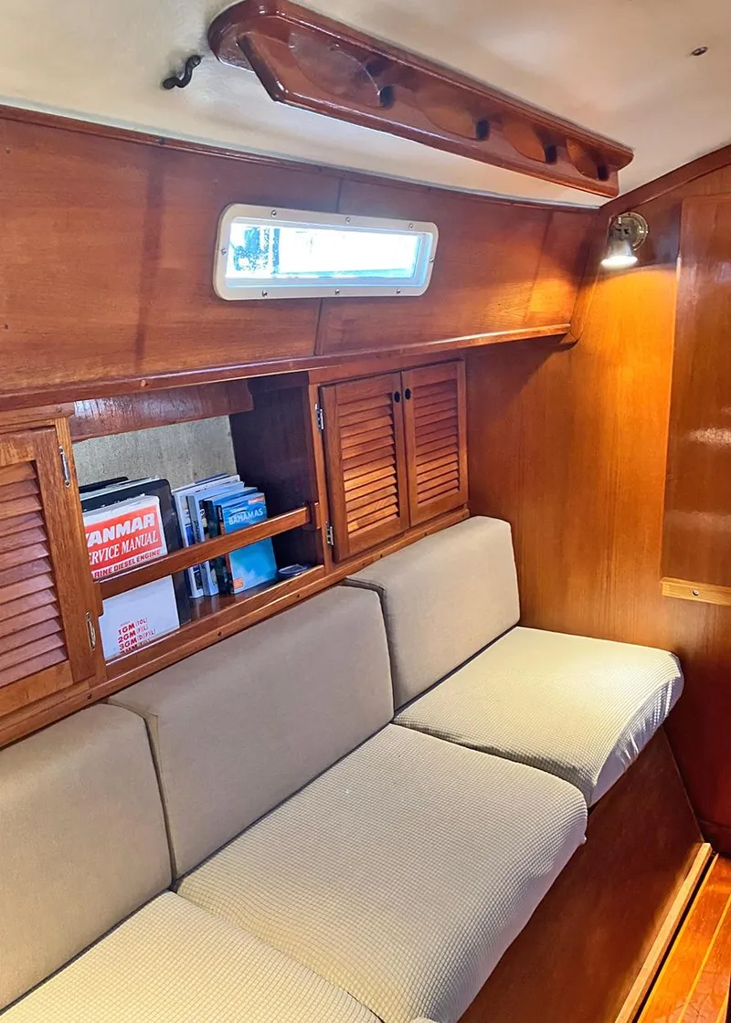 Slide: The Image of 1983 Freedom Cat Ketch interior with wooden cabinets, cushioned seating, and nautical decor. - 12