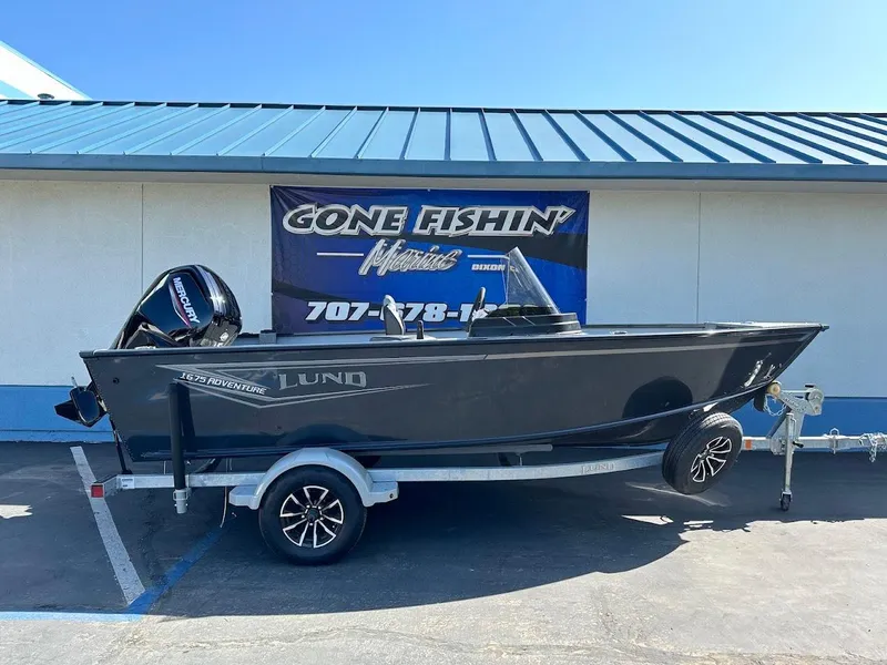 Slide: The Image of 2025 Lund 1675 Adventure SS boat on trailer, parked outside a building. - 1