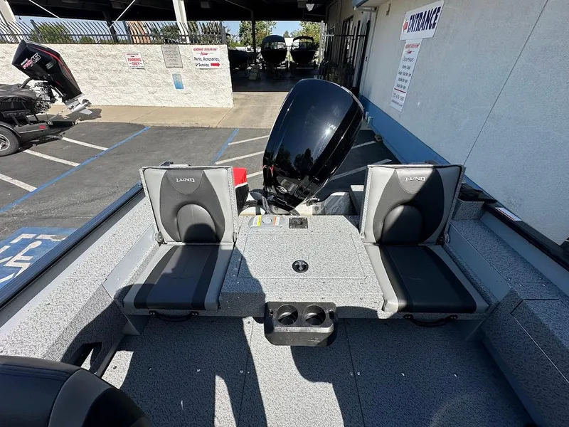 Slide: The Image of 2025 Lund 1675 Adventure SS boat interior with seating and motor, parked in a lot. - 11