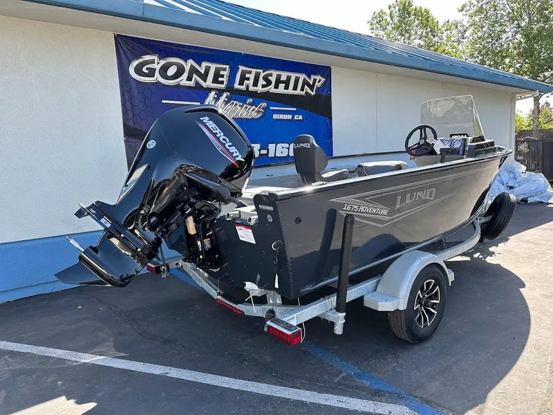 Slide: The Image of 2025 Lund 1675 Adventure SS boat on trailer, parked outside a fishing store. - 7