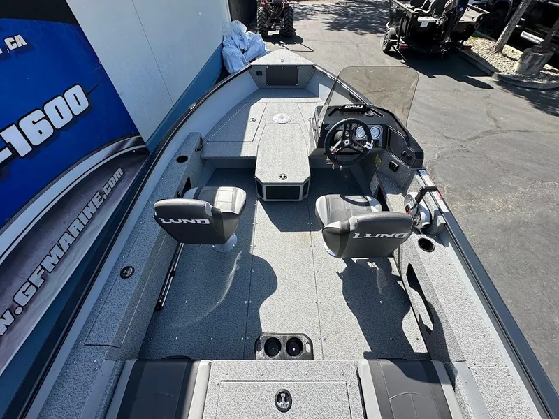 Slide: The Image of 2025 Lund 1675 Adventure SS boat interior with seating and console, parked outdoors. - 9