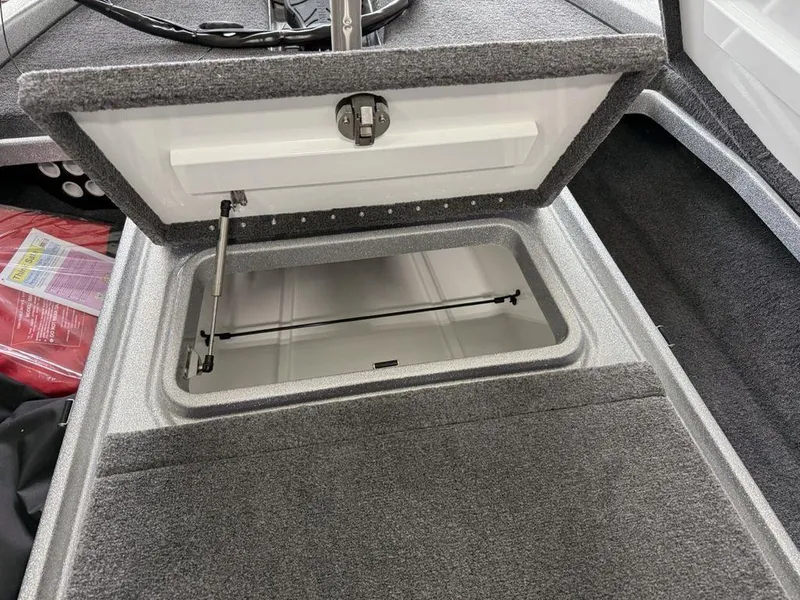 Slide: The Image of Open storage compartment in 2025 Phoenix 920 Elite II boat, featuring gray carpeted interior. - 10