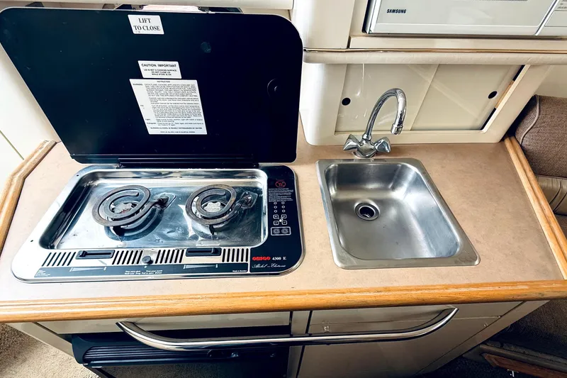 Slide: The Image of Compact kitchen area in a 1998 Maxum 2700 SCR boat with stove and sink. - 11