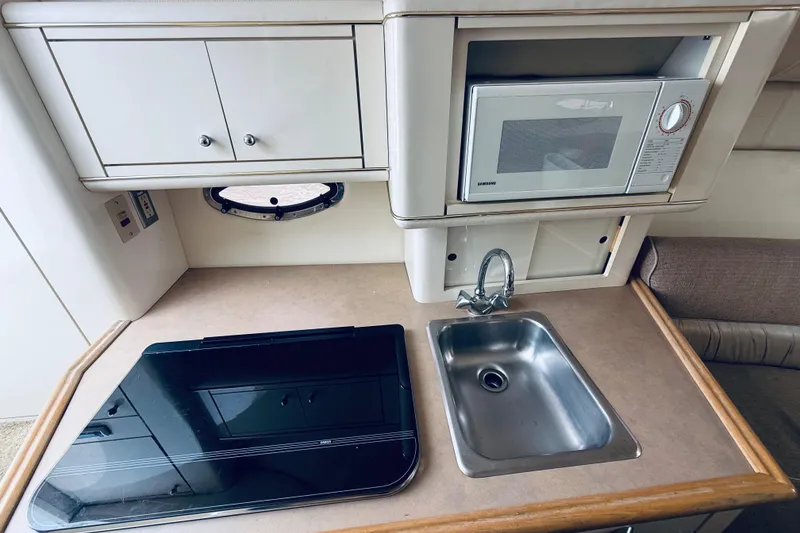 Slide: The Image of 1998 Maxum 2700 SCR boat kitchenette with sink, stove, microwave, and storage cabinets. - 12