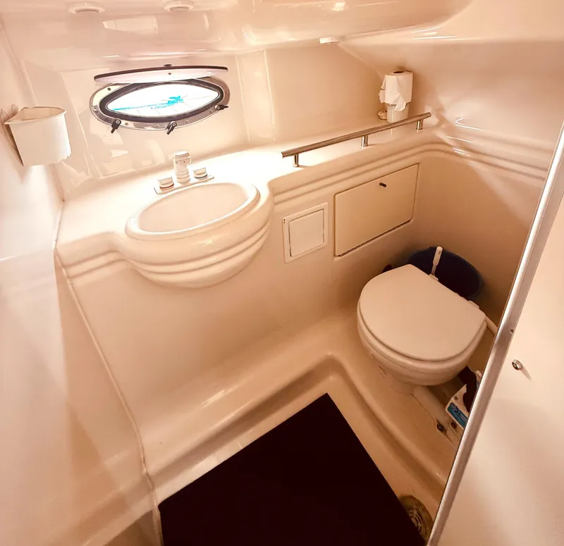 Slide: The Image of 1998 Maxum 2700 SCR boat bathroom with sink, toilet, and porthole window. - 14