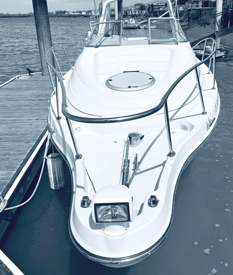 Slide: The Image of 1998 Maxum 2700 SCR boat docked by the water, showcasing sleek design and white exterior. - 2