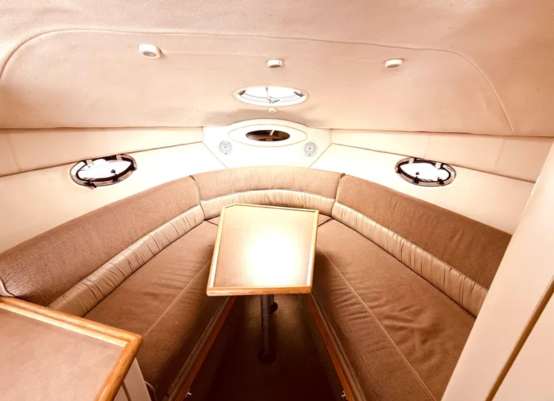 Slide: The Image of 1998 Maxum 2700 SCR boat interior with beige seating and wooden table. - 8