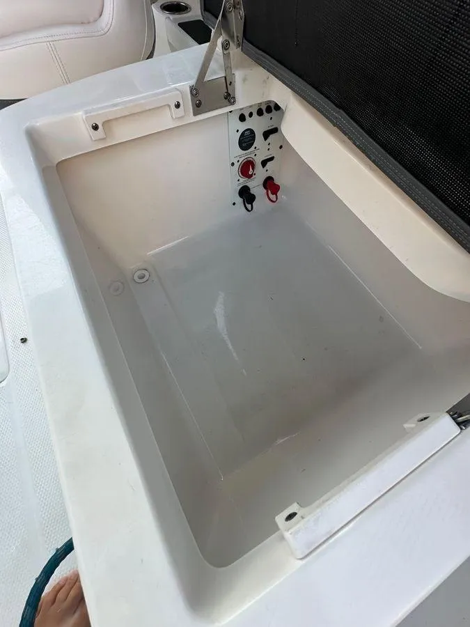 Slide: The Image of 2014 Chaparral 257 SSX boat storage compartment with control panel and white interior. - 11