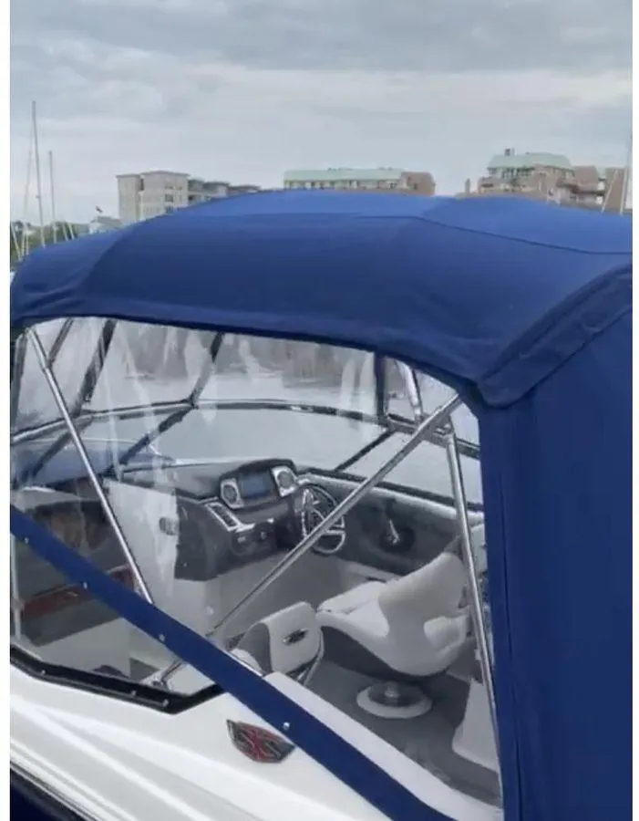 Slide: The Image of 2014 Chaparral 257 SSX boat with blue canopy and modern cockpit, docked at marina. - 2